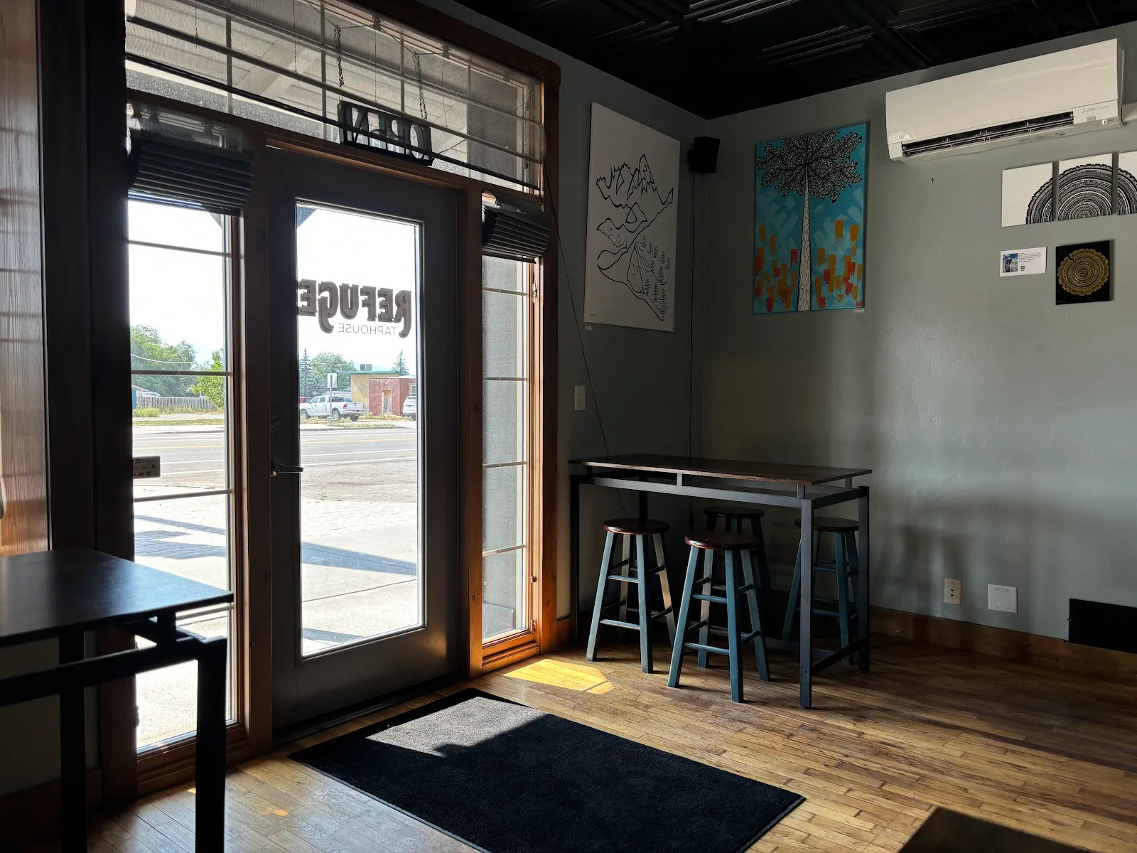 High-top tables by the front windows, with local art on the walls